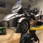Austin Martin makes some repairs to his three-wheeled Spyder motorcycle.