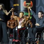 Sheila Brown (left) and IFBB pro-bodybuilder, Johnny Quinn present third-place winner Kris Dim at the 2019 Mr. Olympia in Las Vegas, Nev. (Photo by Christopher Di Virgilio/SNS).